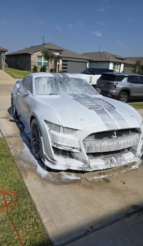 Shelby Mustang covered in thick foam in a driveway