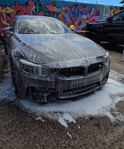 Car covered in cleaning foam before detailing
